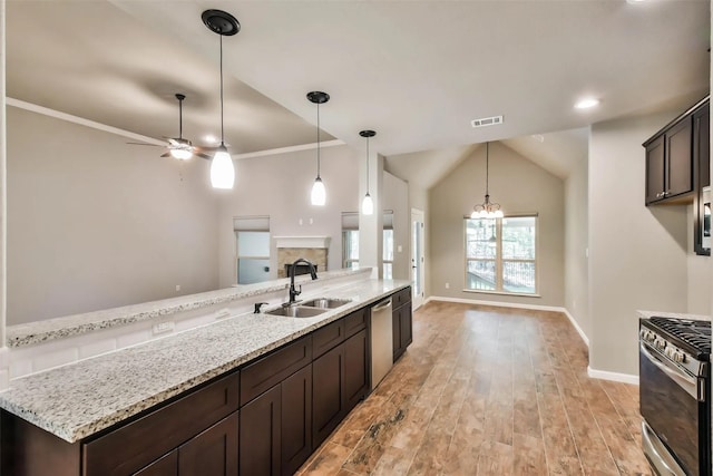 kitchen with light stone counters, appliances with stainless steel finishes, sink, and dark brown cabinets