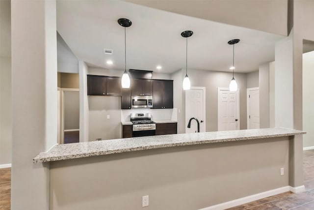 kitchen with hanging light fixtures, stainless steel appliances, sink, and light stone countertops