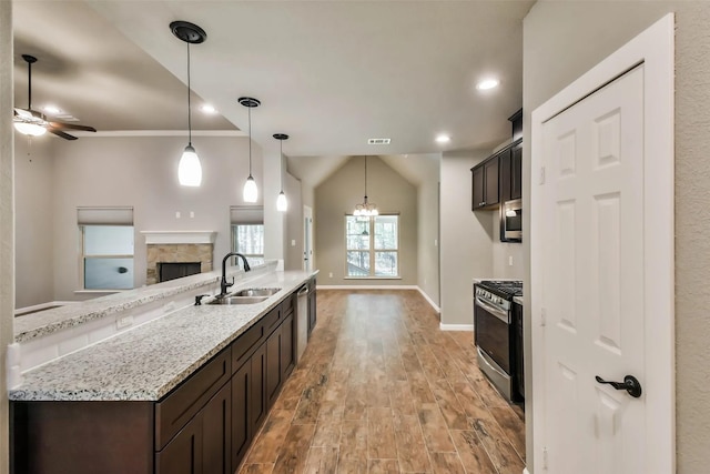 kitchen with stainless steel appliances, dark brown cabinets, sink, and decorative light fixtures