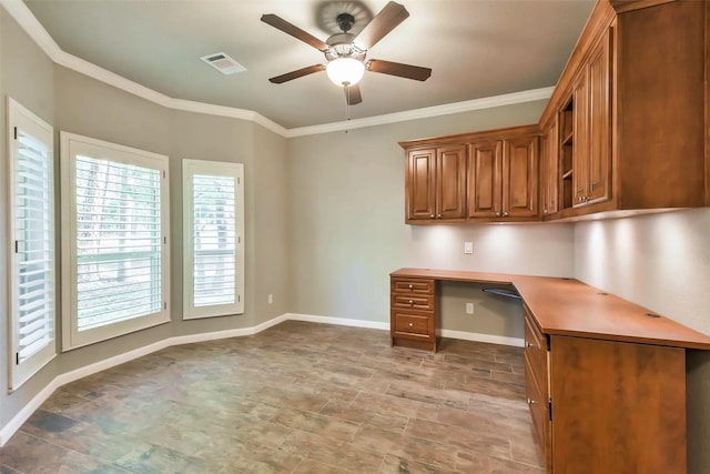 unfurnished office with ceiling fan, ornamental molding, and built in desk