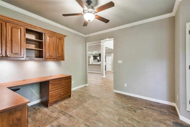 unfurnished office featuring crown molding, ceiling fan, built in desk, and hardwood / wood-style flooring