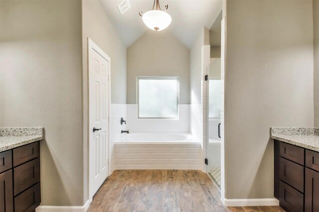 bathroom featuring vaulted ceiling, vanity, shower with separate bathtub, and wood-type flooring