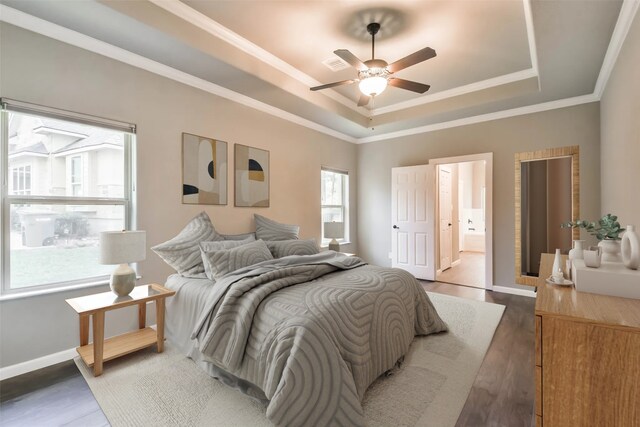 bedroom with connected bathroom, ceiling fan, a tray ceiling, crown molding, and dark wood-type flooring