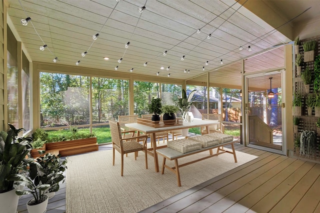 sunroom featuring rail lighting and a wealth of natural light