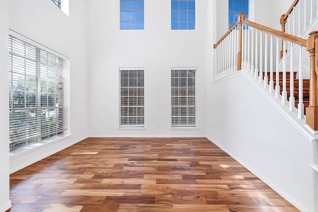 unfurnished living room featuring a towering ceiling and wood-type flooring