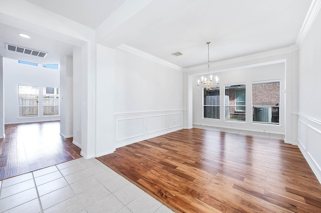 unfurnished dining area with an inviting chandelier, ornamental molding, and light hardwood / wood-style floors