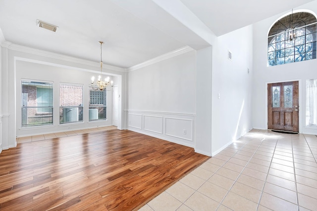 foyer entrance with crown molding, a chandelier, and light hardwood / wood-style flooring