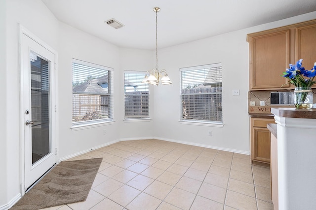 unfurnished dining area featuring an inviting chandelier and light tile patterned flooring