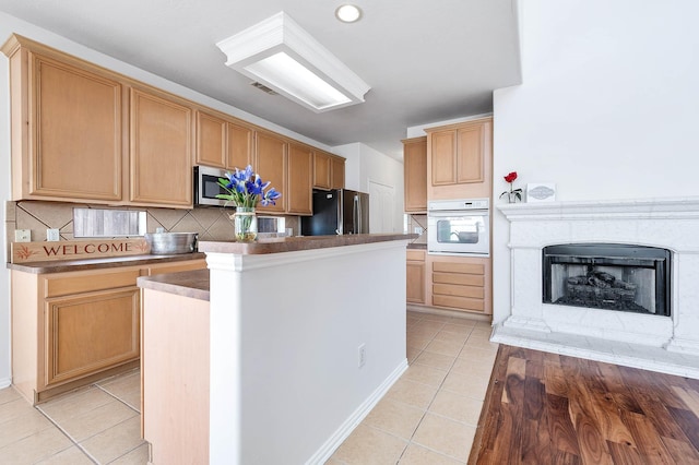 kitchen with black fridge, tasteful backsplash, light tile patterned floors, a kitchen island, and oven