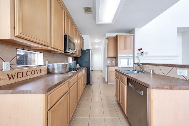 kitchen with backsplash, stainless steel appliances, sink, and light tile patterned floors