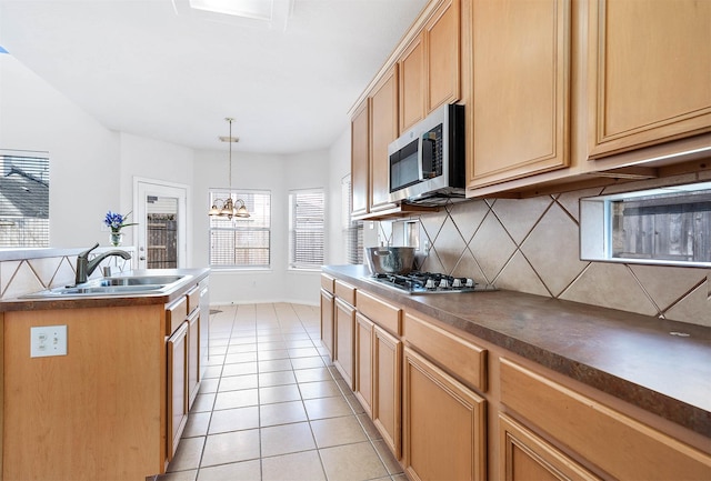 kitchen with sink, light tile patterned floors, appliances with stainless steel finishes, decorative backsplash, and decorative light fixtures