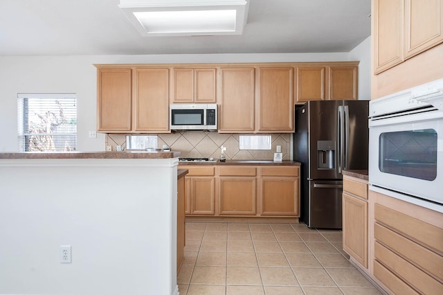 kitchen featuring tasteful backsplash, light tile patterned floors, light brown cabinets, and appliances with stainless steel finishes