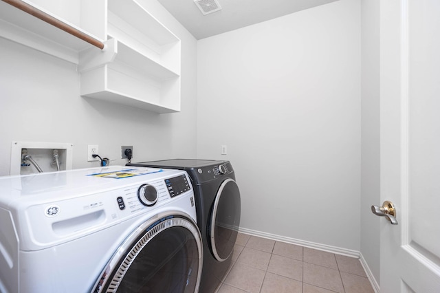 laundry area featuring separate washer and dryer and light tile patterned floors