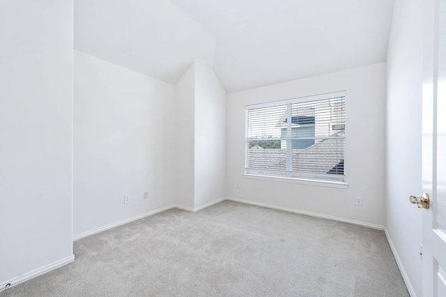 carpeted spare room featuring vaulted ceiling