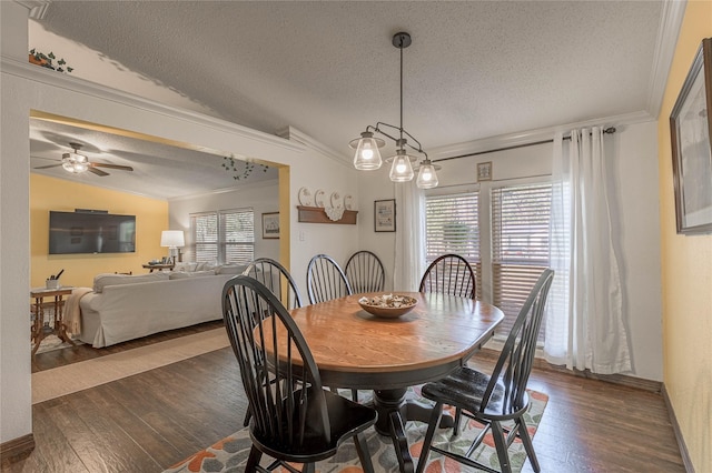 dining area featuring vaulted ceiling, ceiling fan, crown molding, dark wood-type flooring, and a textured ceiling