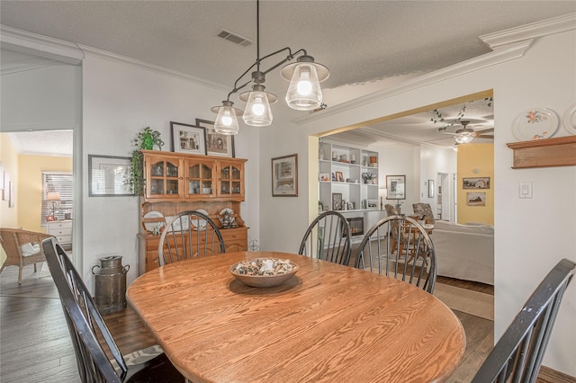 dining space featuring ceiling fan, ornamental molding, dark hardwood / wood-style floors, and a textured ceiling