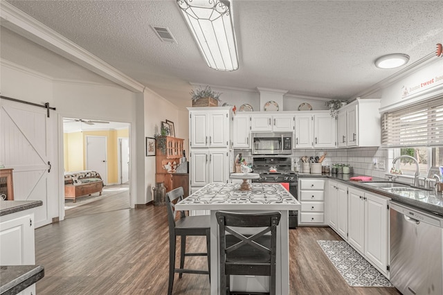 kitchen featuring sink, stainless steel appliances, a center island, white cabinets, and a barn door