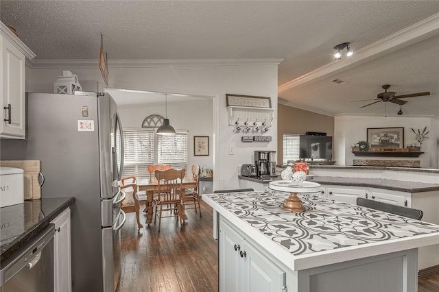 kitchen featuring vaulted ceiling, appliances with stainless steel finishes, a kitchen island, pendant lighting, and white cabinets