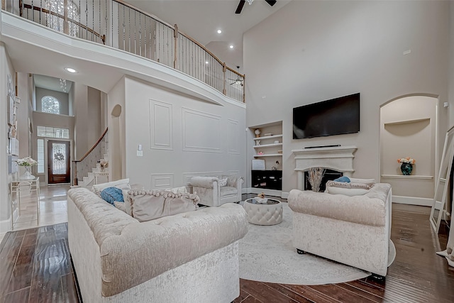 living room with built in shelves, dark hardwood / wood-style floors, and a high ceiling