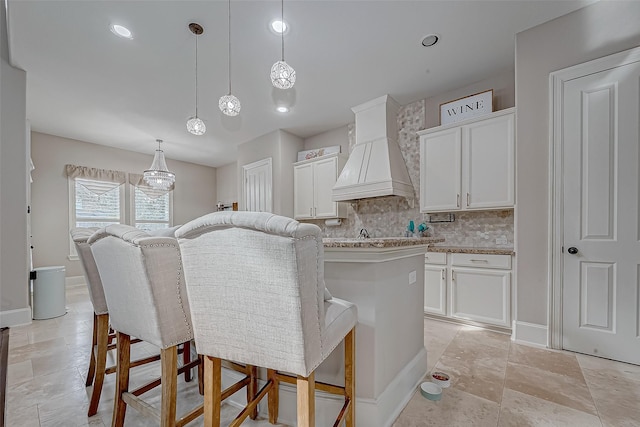 kitchen with custom exhaust hood, a center island, white cabinets, and decorative light fixtures