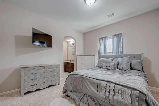 bedroom with light colored carpet and ensuite bathroom