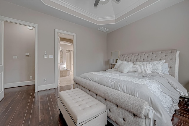 bedroom with dark hardwood / wood-style floors, ceiling fan, connected bathroom, and a tray ceiling