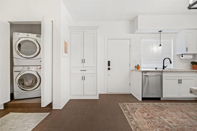 laundry area featuring stacked washer and dryer, sink, and dark hardwood / wood-style floors