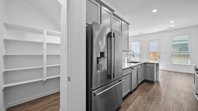 214 Fulton Station Dr, Houston, TX 77009 - kitchen with stainless steel appliances, a sink, dark wood finished floors, gray cabinetry, and light stone counters