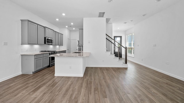 214 Fulton Station Dr, Houston, TX 77009 - kitchen with a sink, backsplash, wood finished floors, gray cabinetry, and appliances with stainless steel finishes