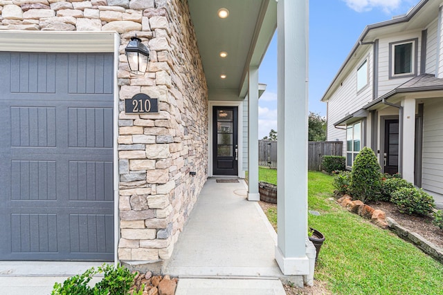 doorway to property featuring a garage and a lawn