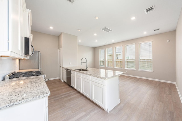 kitchen featuring light stone countertops, white cabinetry, appliances with stainless steel finishes, and sink