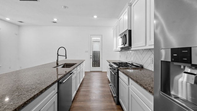 kitchen featuring stainless steel appliances, sink, white cabinets, and dark stone counters