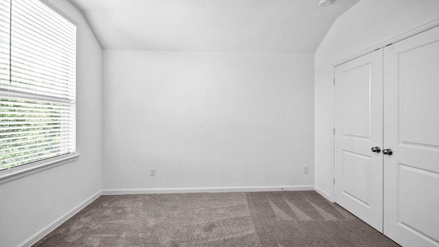 unfurnished bedroom with carpet floors, a closet, and vaulted ceiling