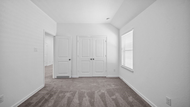 unfurnished bedroom featuring carpet flooring, vaulted ceiling, and a closet