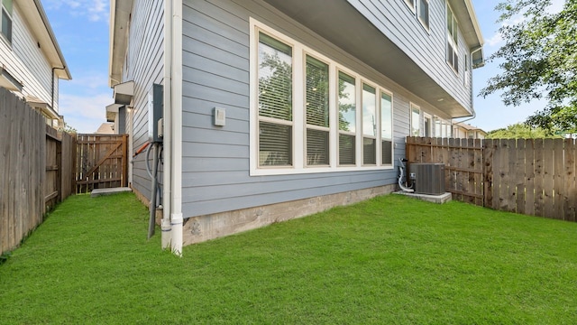 view of side of home featuring cooling unit and a yard