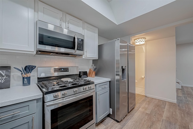 kitchen with stainless steel appliances, tasteful backsplash, white cabinetry, and light wood-type flooring