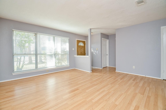 unfurnished room with a textured ceiling and light wood-type flooring