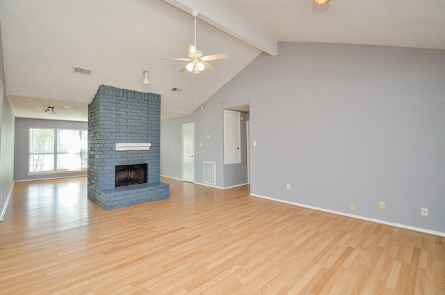 unfurnished living room featuring ceiling fan, beam ceiling, a brick fireplace, and light hardwood / wood-style flooring