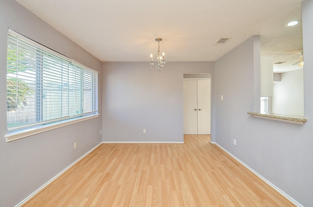 spare room with an inviting chandelier and light hardwood / wood-style flooring