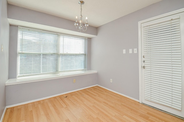 spare room with an inviting chandelier and hardwood / wood-style floors