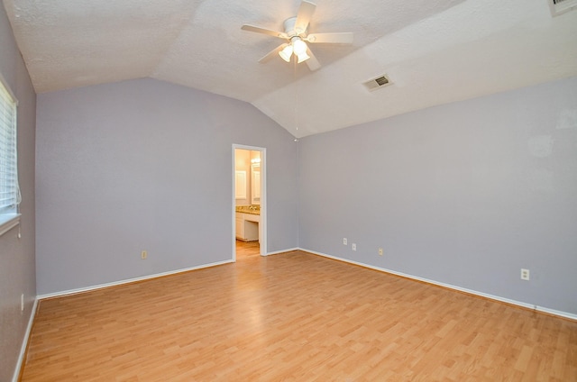 empty room featuring a textured ceiling, vaulted ceiling, ceiling fan, and light wood-type flooring