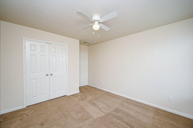 unfurnished bedroom with light carpet, ceiling fan, and a closet