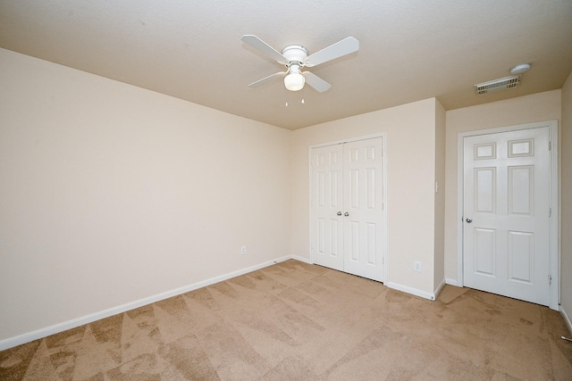 unfurnished bedroom featuring light carpet, a closet, and ceiling fan