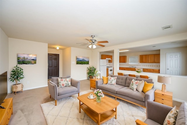 carpeted living room with ceiling fan and sink