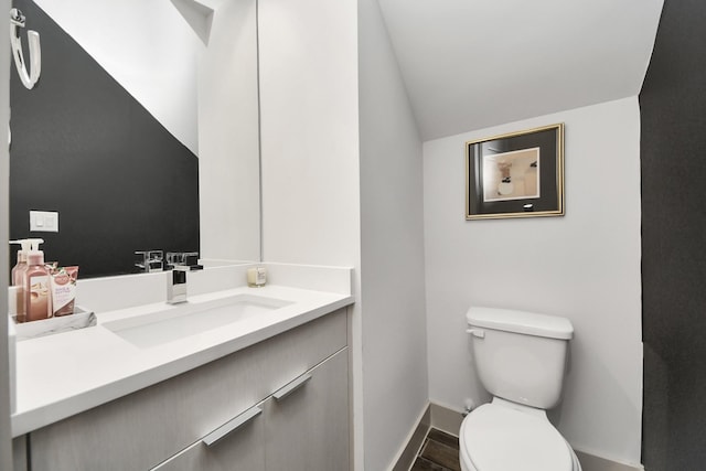 bathroom with lofted ceiling, vanity, and toilet