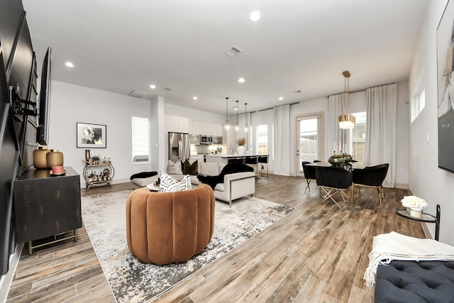 living area with light wood-style flooring, recessed lighting, and visible vents