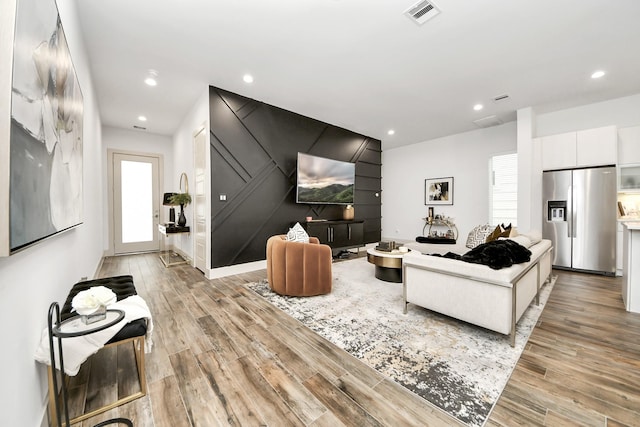 living area featuring recessed lighting, light wood-style floors, visible vents, and a wealth of natural light