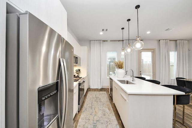 kitchen with appliances with stainless steel finishes, decorative light fixtures, sink, and white cabinets