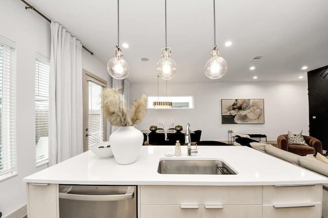 kitchen featuring pendant lighting, sink, an island with sink, and dishwasher