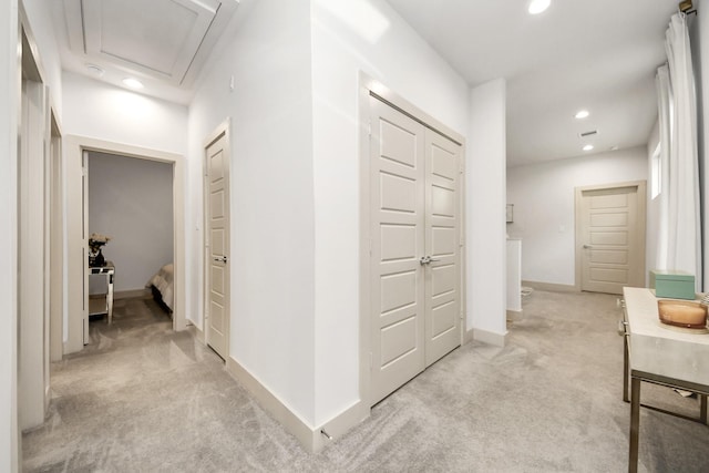 hallway with light carpet, recessed lighting, attic access, and baseboards